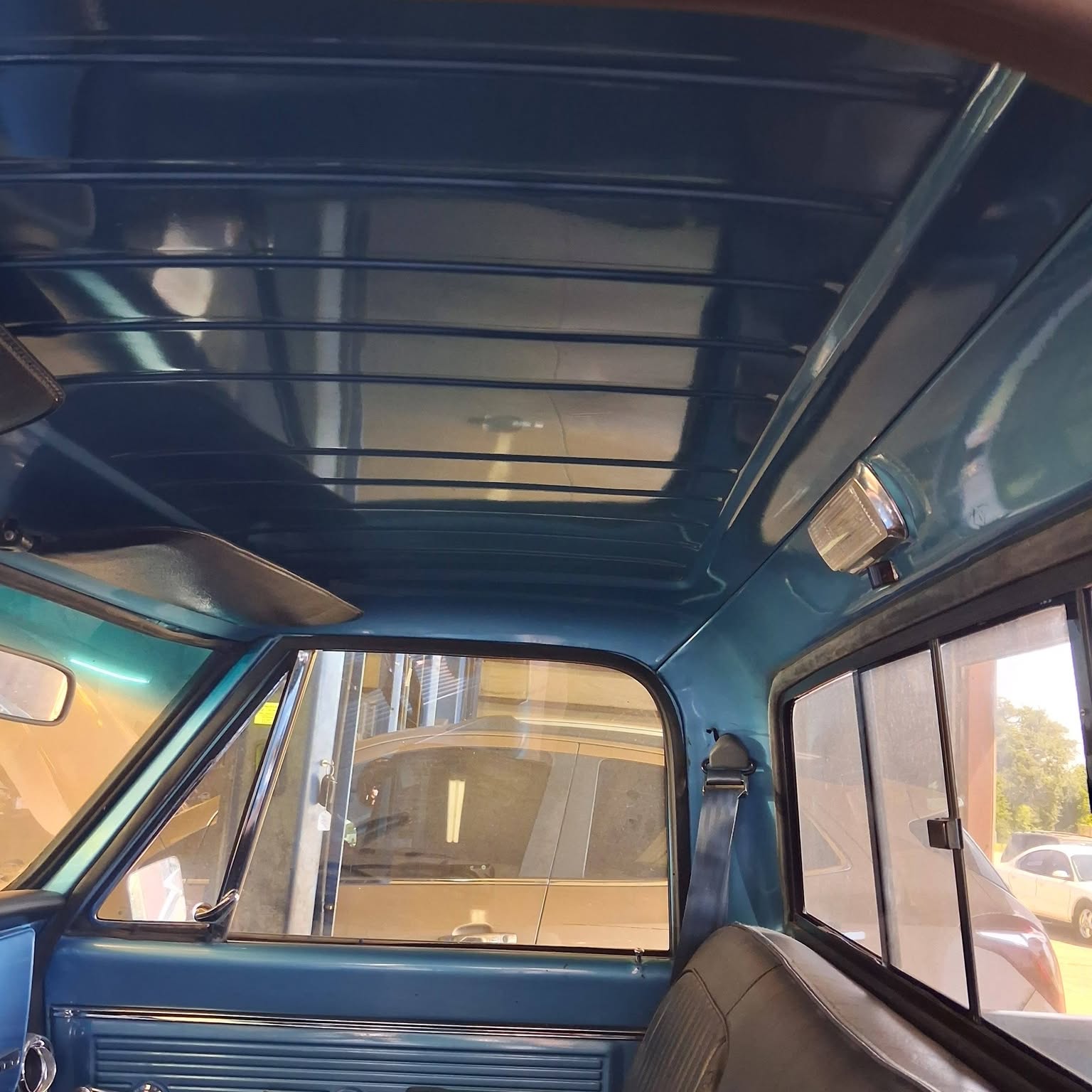 Teal cabin and sliding rear window of a vintage truck in the shop.